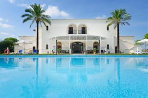 图列坦尼他拉润尼斯度假酒店的棕榈树建筑前的大型游泳池
