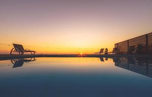 沃丽曼村Orient Villas Deluxe的一个带椅子的游泳池,享有日落美景