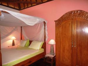 罗威那萨拉斯瓦蒂度假屋 的一间卧室配有天蓬床和橱柜