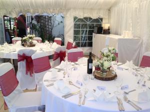 艾尔斯伯里The Swan at Great Kimble的一张桌子,用来举办婚礼,上面有白色的桌子和红色的椅子