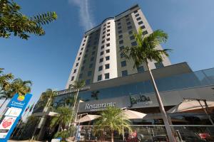 龙多诺波利斯伦多诺波利斯舒适套房酒店的一座高大的建筑,前面有棕榈树