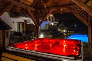 Krajno PierwszeApartamenty Pod Łysicą & SPA - przy stoku, basen, jacuzzi, sauna的晚上在后院里设有一个红色浴缸