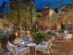 巴塞罗那H10卡萨含羞草4*索普酒店的庭院设有桌椅,棕榈树