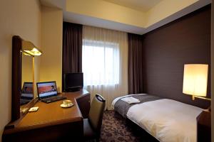 春日井胜川广场酒店的酒店客房配有一张床、一张书桌和一台笔记本电脑