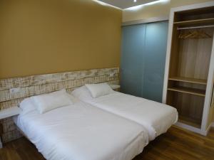 布尔戈斯Urban Burgos的卧室配有2张白色的床和衣柜。