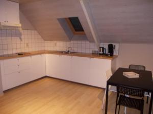 阿伦东克Het Zolderhuis的厨房配有白色橱柜和桌子