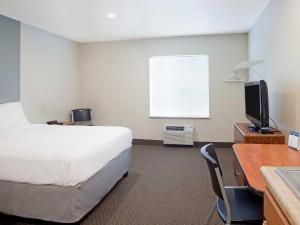 迪金森Suburban Studios的酒店客房配有一张床、一张书桌和一台电视。