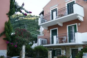 卡拉米Garneli Apartments的粉红色的公寓楼,设有阳台和鲜花