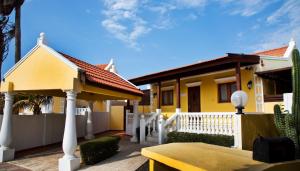 SoledadCunucu Villa with Private Jacuzzi的黄色的房子,有白色的栅栏和桌子