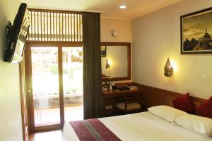 婆罗浮屠曼诺哈拉假日酒店的一间卧室配有一张床、一张书桌和一个窗户。