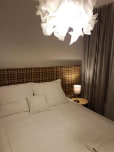 波兹南CCH大象公寓 的卧室配有白色的床和吊灯。