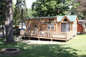 EdgertonLakeland RV Campground Deluxe Loft Cabin 11的小木屋设有门廊和树