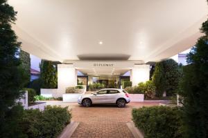 堪培拉Ramada Diplomat Canberra的停在大楼前的白色汽车