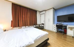 大田水晶住宅酒店的一间卧室配有一张床、一张书桌和一台电视
