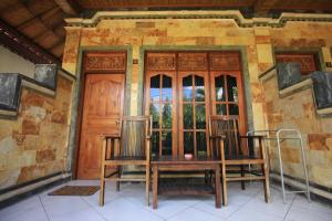 蓝梦岛捷鹏巴厘岛别墅 的门廊配有两把椅子和一张桌子,门