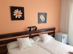圣地亚哥德拉里贝拉K-西托旅馆的卧室配有2张白色的床,墙上挂着2朵鲜花
