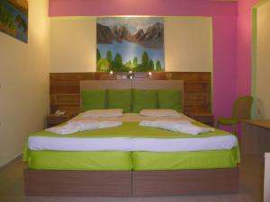阿凯松米拉贝尔酒店的卧室配有一张绿色的床,墙上挂有绘画作品