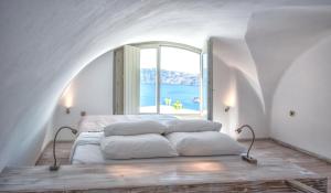 伊亚La Perla Villas and Suites - Adults Only的一张位于带大窗户的房间内的床铺