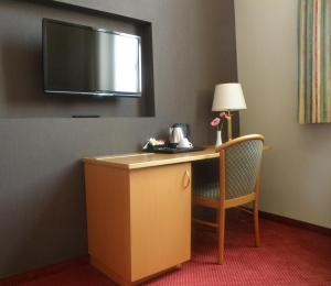 伊普尔阿尔比恩酒店的酒店客房设有一张桌子和一台墙上的电视