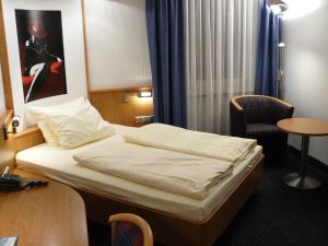 斯图加特Mirage City Hotel Stuttgart Zentrum的配有一张床和一把椅子的酒店客房