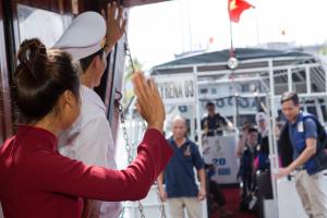 下龙湾美人鱼号邮轮酒店的女人站在船上,手举着