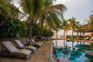 美奈Sailing Club Resort Mui Ne的一个带躺椅的度假村游泳池,并种植了棕榈树
