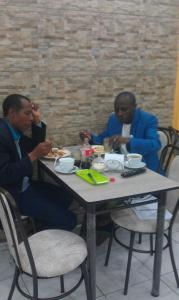 基多Hotel Villamar的三个男人坐在桌子上吃食物