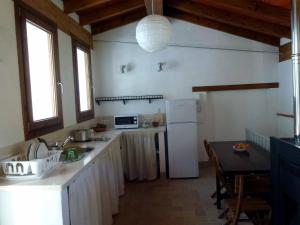 贝纳马奥马Casa Rural El Aljibe的厨房配有白色冰箱和桌子
