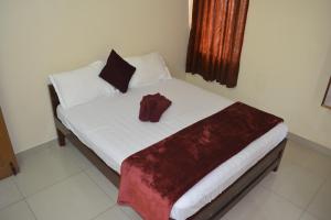 马伊拉杜图赖JP Nivaas Guest House的一间卧室配有一张红色浴袍的床