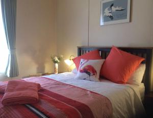 卡斯尔梅恩考卡布瑞度假屋的一间卧室配有红色和橙色枕头的床