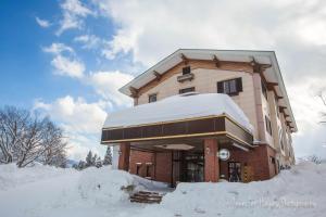 妙高妙高森野山林小屋的一座被雪覆盖的建筑,周围积雪覆盖