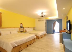 鹅銮鼻蔚蓝海舍的两张床位于带黄色墙壁的酒店客房
