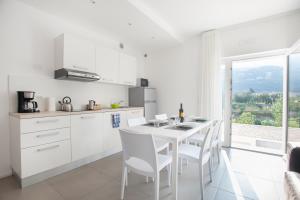 托尔博莱Appartamenti Villa al Fiume的白色的厨房配有桌椅和窗户