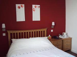 普里茅斯Mountbatten Hotel的卧室配有白色的床和红色的墙壁