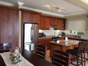 苏莎亚Hispaniola 2-Bedroom Ground Floor的厨房配有木制橱柜和不锈钢冰箱。