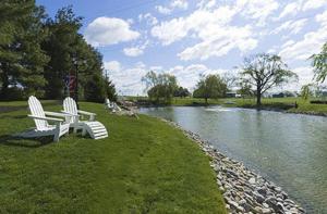 兰开斯特富尔顿斯廷博特酒店 的两把白色椅子坐在河边的草地上