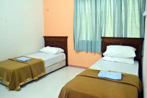 哥打巴鲁Homestay Kota Bharu, Telipot的配有橙色墙壁和蓝色窗帘的客房内的两张床