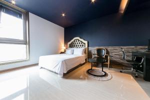 首尔SB汝矣岛精品酒店的一间卧室配有一张床、一张桌子和一把椅子