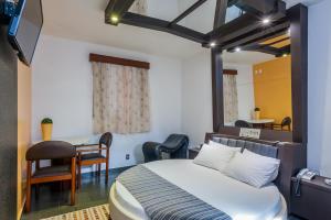 伊图佩瓦彩虹汽车旅馆（仅限成人）的卧室配有一张床和一张桌子及椅子