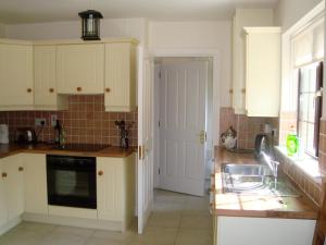 莫希尔Lough Rynn Self Catering的厨房配有白色橱柜、水槽和窗户。