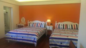 九份九份黄金屋的一间卧室设有两张床和橙色的墙壁