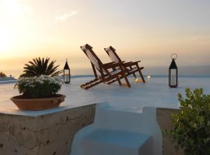 伊亚OIA UNIQUE HOMES by K&K的两把木椅位于俯瞰着大海的庭院