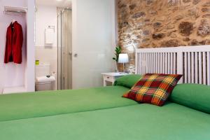 圣地亚哥－德孔波斯特拉Pensión Rua Nova的一间卧室设有绿色的床和石墙