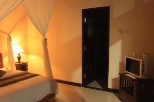 坎古艾力特巴厘岛别墅的一间卧室配有一张床,另一扇门配有电视