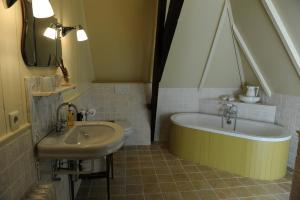 OostwoldMoushouk Bed and Breakfast的浴室设有水槽和水槽旁的浴缸