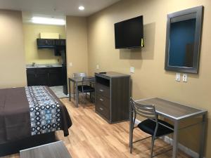 贝敦Deluxe Inn & Suites - Baytown的小房间设有一张床、一张桌子和椅子