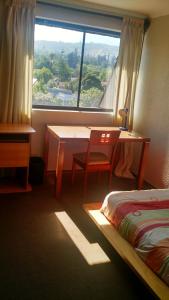 圣地亚哥Habitaciones en Departamento的客房设有床、书桌和窗户。