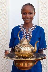 桑给巴尔齐斯瓦楼酒店的把金茶壶放在盘子里的女人
