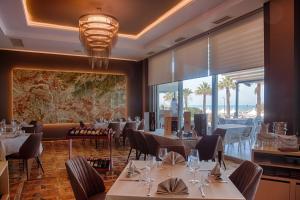 格勒姆高级海滩酒店的餐厅设有桌椅和大窗户。