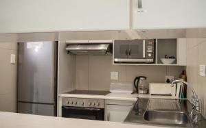 德班802 The Bermudas - by Stay in Umhlanga的厨房配有水槽和不锈钢冰箱